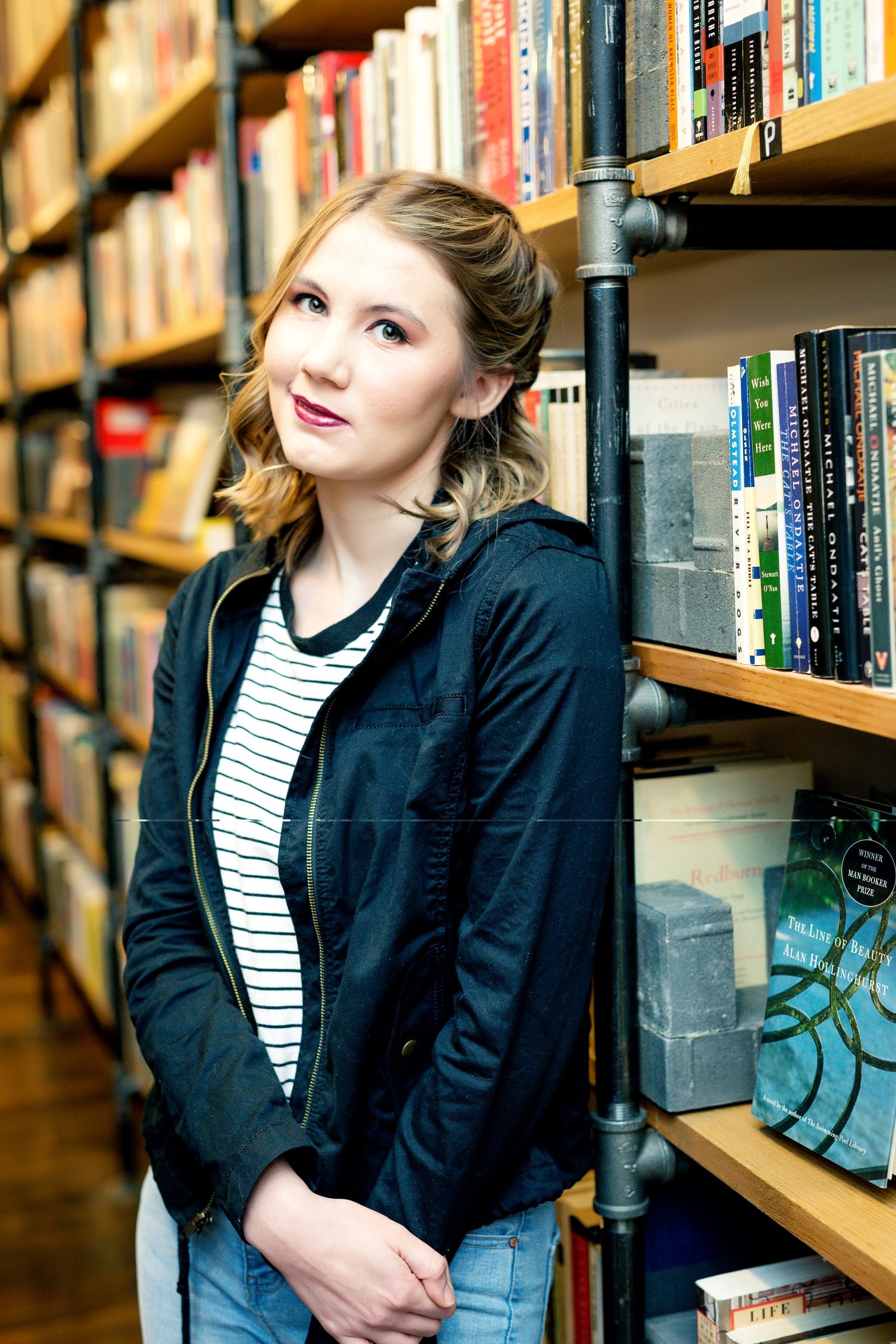 Girl standing in bookstore up against a bookshelf 