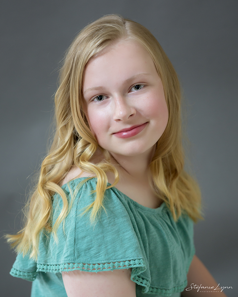 school age girl smiling at camera, wearing a green top.